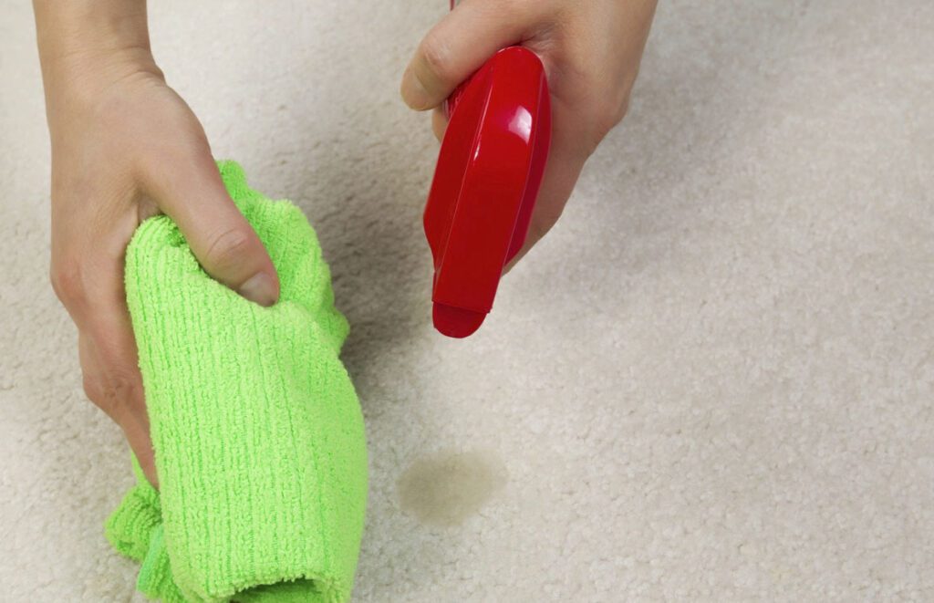 A person holding a red object and cleaning it with green cloth.