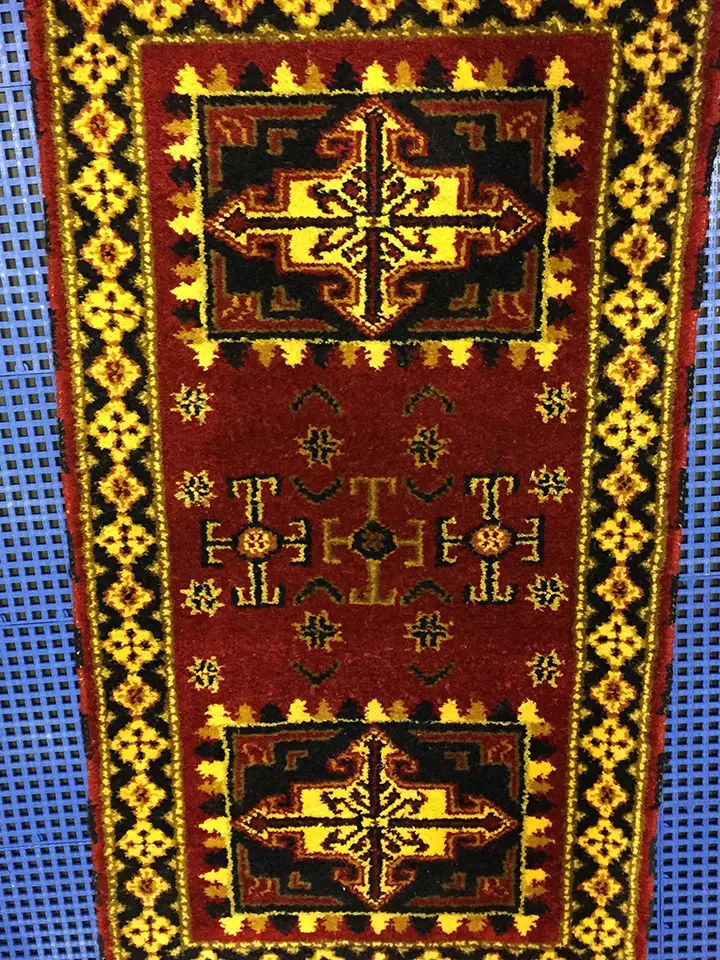 A red and yellow rug with black border