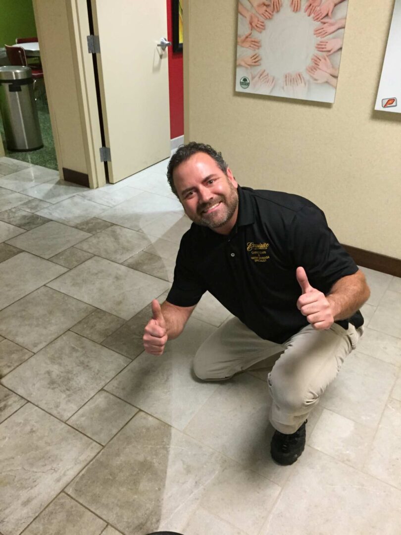 A man kneeling on the floor in front of a wall.