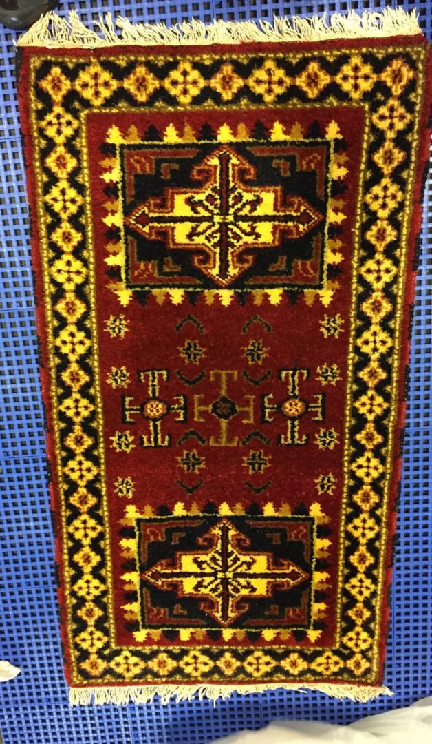 A red and yellow rug with designs on it.