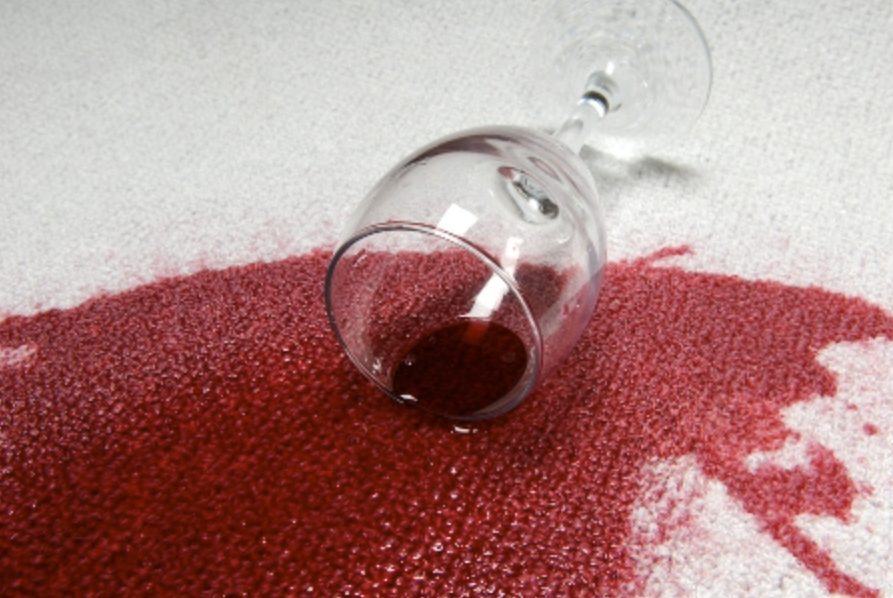An empty wine glass lies on a textured red and white surface.