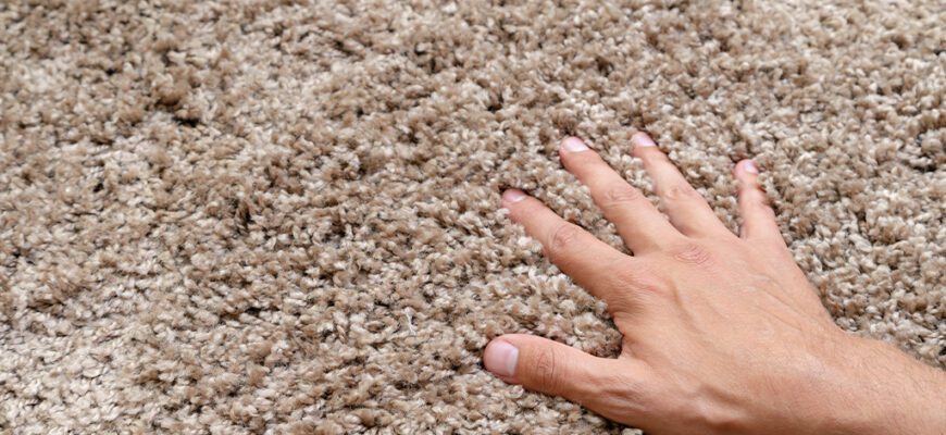Hand touching soft, textured carpet fibers.
