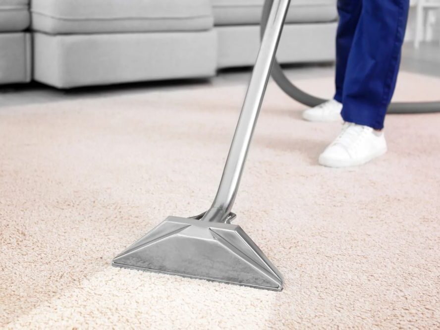 Person vacuuming a carpet in a living room.
